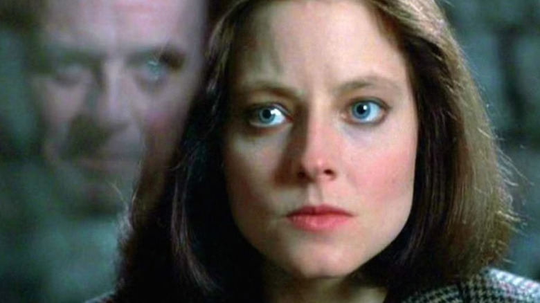 Clarice looking intense with the reflection of Hannibal Lecter in the glass next to her, a scene from The Silence of the Lambs