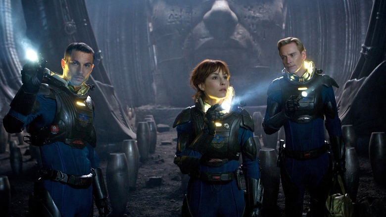 Logan Marshall-Green as Charlie Holloway, Noomi Rapace as Elizabeth Shaw, and Michael Fassbender as David exploring an unknown room filled with oval containers in Prometheus